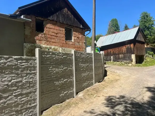 Betónový plot s drevodekorom pri starom dome