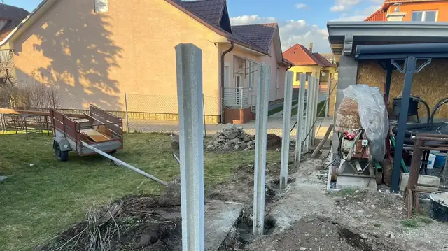 Pred: osadené betónové stĺpiky a rozkopaný pozemok